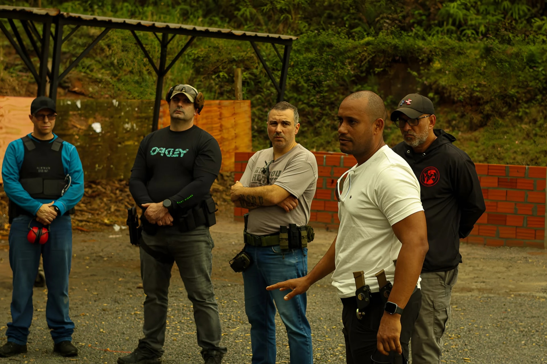 Instrutor Neres explicando um exercício para a turma reunida em semicírculo no estande